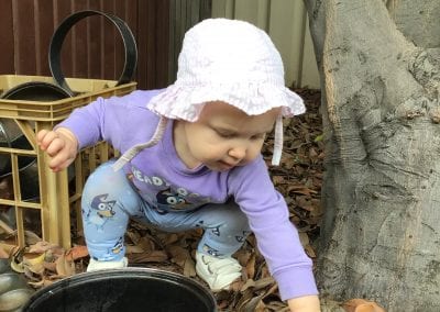 child playing with leaves at daycare Mayfield